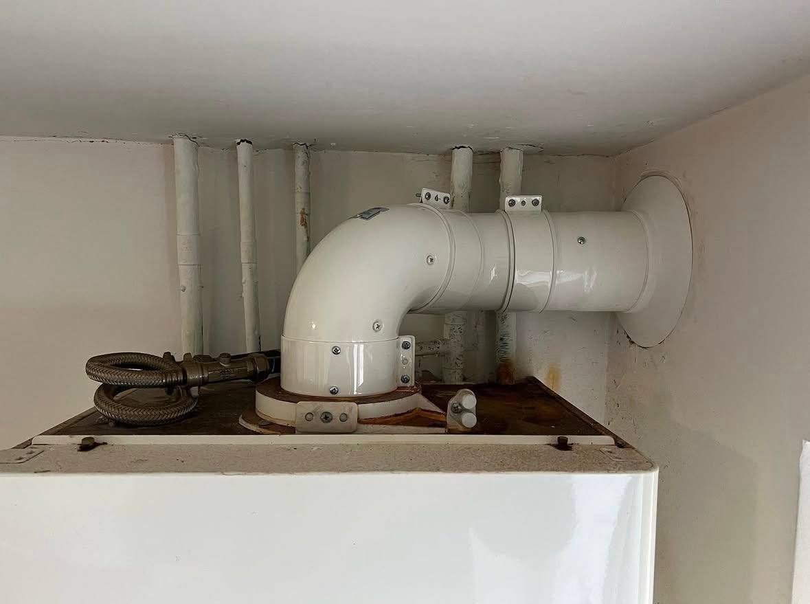 New white boiler flue run and wall terminal fitted above a boiler